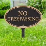 No Trespassing Plaque Oval Shape Black & Gold in yard